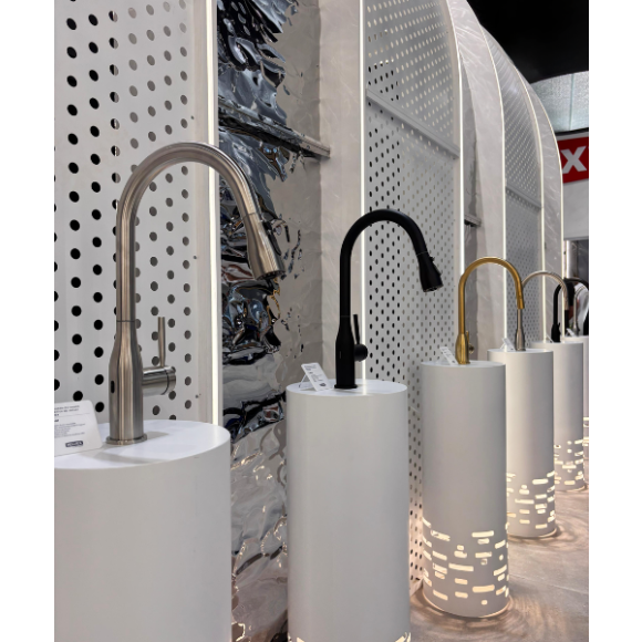 Grifería para cocina en diversos acabados de Helvex en Obra Blanca 2025 en stand blancos con iluminación en la parte baja.