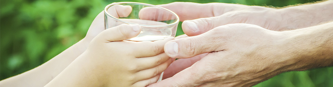 Manos juntas sosteniendo un vaso de agua por el cuidado del agua en fondo de plantas